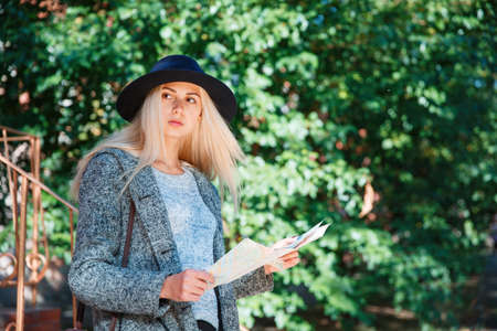 The girl is holding a map. Outside.