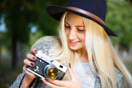 The girl looks at the photo on the camera and smiles. Outside.