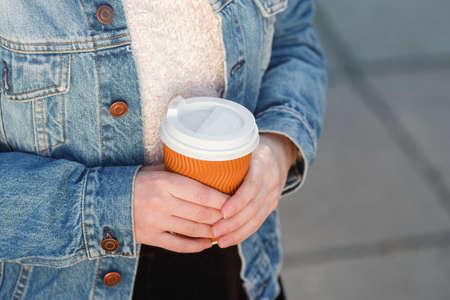 A plastic glass of coffee in the hands of a European girl.の写真素材