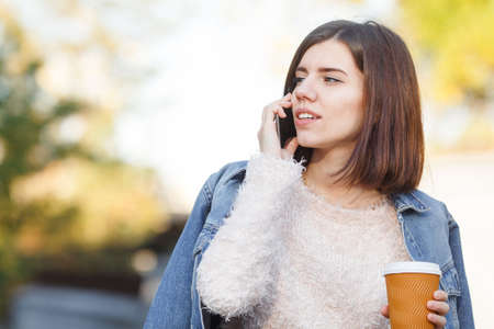 Young brunette speaks on the phone and looks away.
