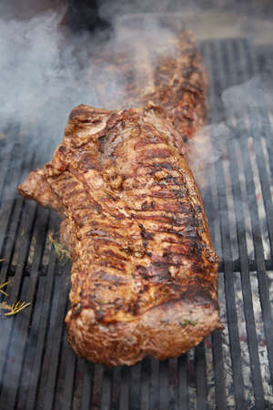 Steaks fry on a grid with seasonings and herbs on them