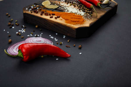 Composition with a cutting board, spices and hot pepper on a wooden backgroundの写真素材