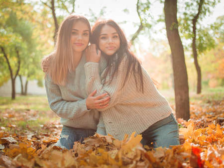 Close-up of beautiful girls, twins sisters, in autumn parkの写真素材