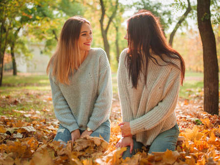 Close-up of beautiful girls, twins sisters, in autumn park