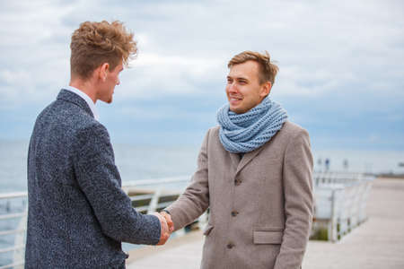 Business men in a coat on the pier shake hands.の写真素材