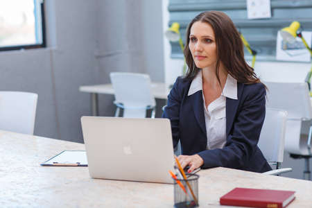 A young brunette is working at her desk at her office.の写真素材
