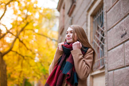 A young girl in a beige coat in the street embraced herselfの写真素材