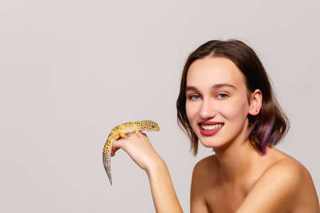 Girl with a lizard on a gray backgroundの写真素材