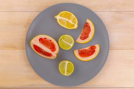 Sliced lemon, lime and grapefruit on a gray plate. View from aboveの写真素材