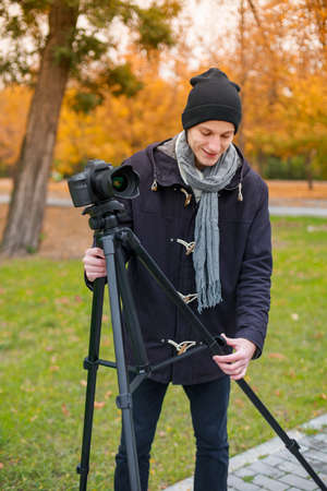 The videoblogger adjusts his camera amid the park