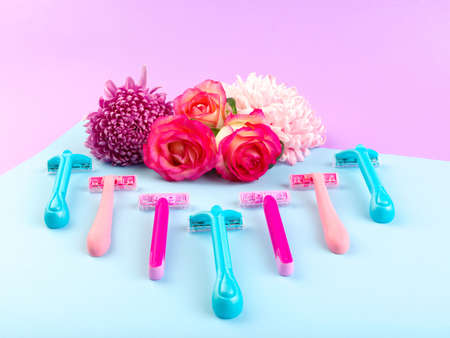 Set for hair removal. Blue and pink womans razor on the colorful background. Beautiful roses and pionies lying near the razors. Close-up of objects.の写真素材