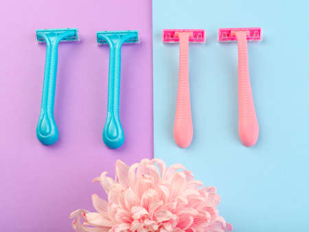 Set for hair removal. Blue and pink womans razor on the colorful background. Beautiful roses and pionies lying near the razors. Close-up of objects.の写真素材