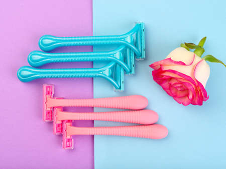 Set for hair removal. Blue and pink womans razor on the colorful background. Beautiful roses and pionies lying near the razors. Close-up of objects.の写真素材