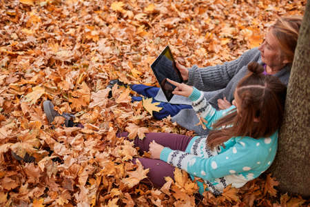 View from above. The granddaughter is showing r on the tablet to his grandmother. They sit in the...