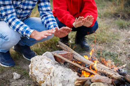 A guy and a girl, are warming their hands near the fire . Outside.の写真素材