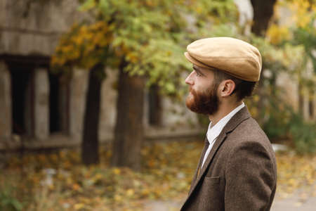 Gangster with a beard staring into the distance standing near an abandoned building. Retro. Outdoors.の写真素材