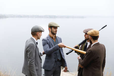 Several gangsters, with weapons and beats argue about something. Retro. Outdoors.の写真素材