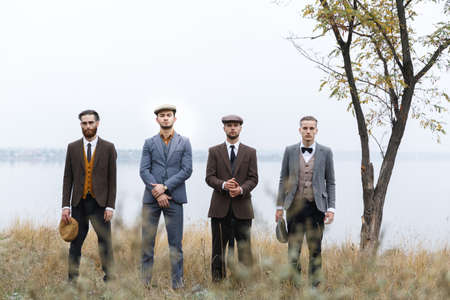 Four serious gangsters stand in a row in the fall. Retro. Outdoors.の写真素材