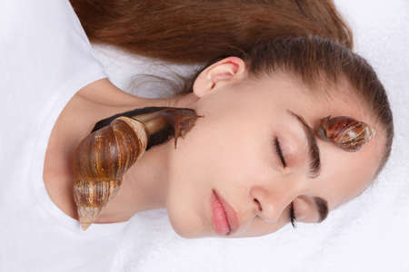 Face of a beautiful girl with snails close-up on a white backgroundの写真素材