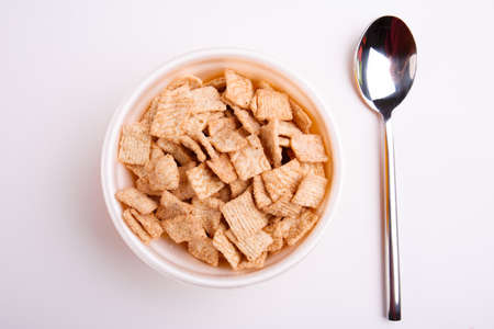 Corn cushions, appetizing cereal, in a plate, next to it lies a spoon on a white background. View from above.の写真素材