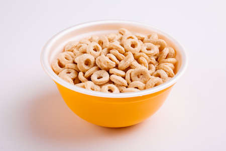 Corn childhood appetizing cereal, rings, in a yellow plate on white background.の写真素材