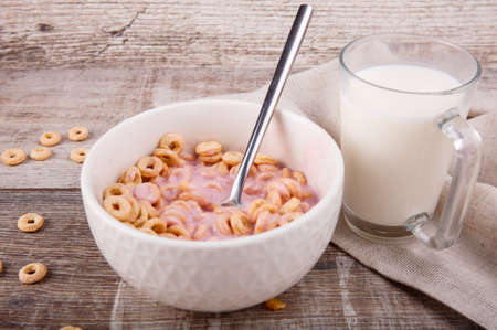 Breakfast, in a corrugated plate corn rings with yogurt and a spoon, next is a glass of milk on...