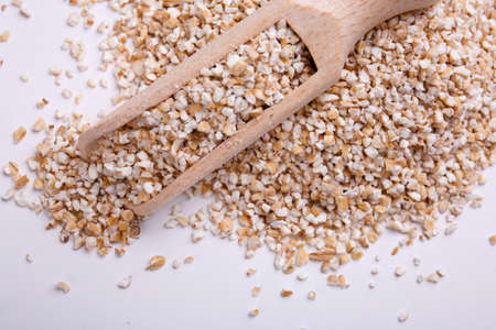A pile of wheat cereals, on it lies a wooden scoop isolated on a white background. View from above.の写真素材