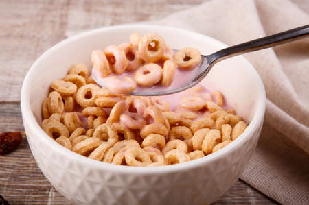 Breakfast, in a corrugated plate corn rings with yogurt, a spoon with rings over a plate, scattered...