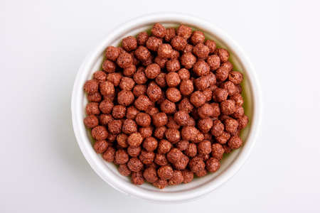 Chocolate balls, appetizing cereal, in a plate, on white background. View from above