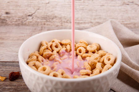 Breakfast, in a bowl of corn rings, add yogurt, scattered raisins on a sacking background.の写真素材