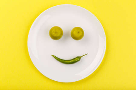 Spicy green pepper with two limes trees on a yellow backgroundの写真素材