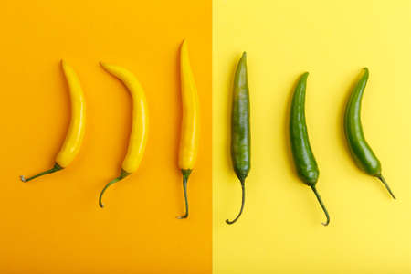 Yellow and green pepper on orange and yellow background verticallyの写真素材