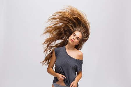 Hot girl with flying hair on a gray backgroundの写真素材