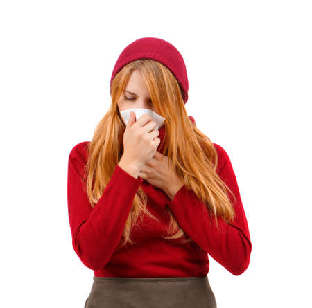 Redhead girl in red hat wiping her nose with a handkerchief on a white isolated backgroundの写真素材