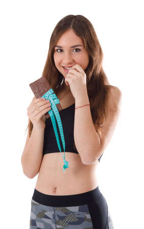 Fitness girl with chocolate bar coiled tape for measuring on white isolated backgroundの写真素材