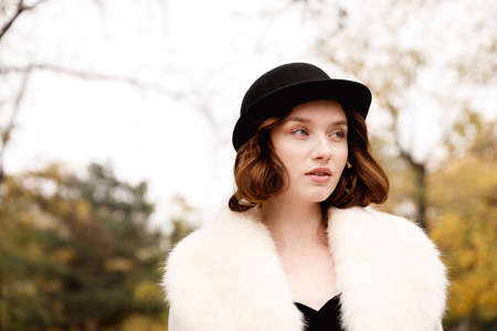 Beautiful girl in retro clothes on a blurred background of autumn parkの写真素材