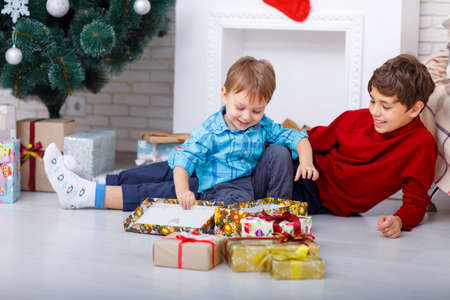 Portrait of charming brothers with Christmas gifts at homeの写真素材