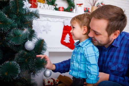 Happy father and his little son decorating the Christmas tree at home.の写真素材
