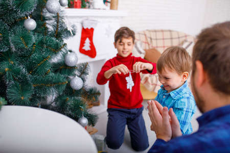 A happy father and his sons decorate the Christmas tree at home, a happy childhood.の写真素材