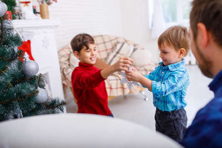 A happy father and his sons decorate the Christmas tree at home, a happy childhood.の写真素材