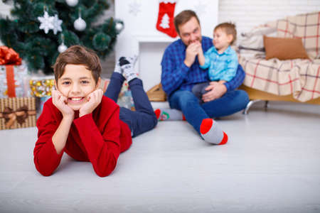Happy father and his sons at home near the Christmas tree.の写真素材