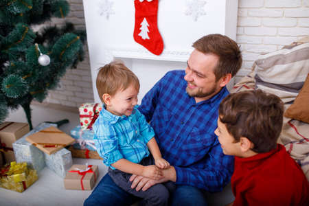 Happy father and his sons at home near the Christmas tree.の写真素材