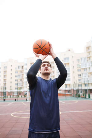 Basketball player in an open stadium with a ball in his hands over his head