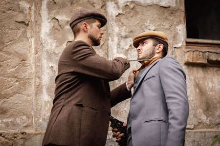 A portrait of retro gangsters are wrestling each other with weapons.の写真素材