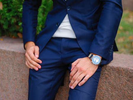 Close-up of a businessman's hand, in a blue suit against a background of green Christmas trees, put his hands on his feet, leaning on the parapet. Business concept, expectation.の写真素材