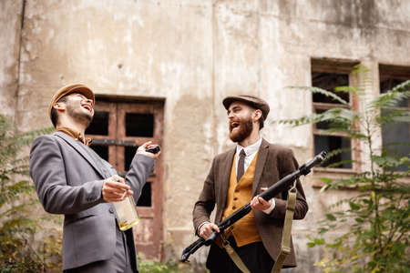 Gangsters on the background of the old abandoned building laugh. In the hands of arms, alcohol, and cigarettes.の写真素材