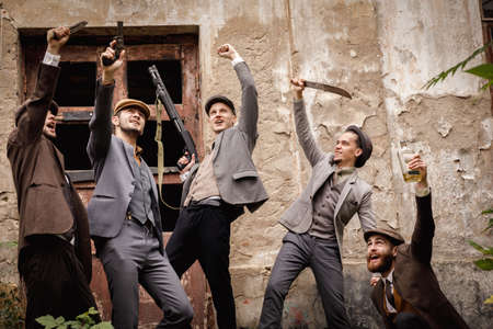 A group of gangsters with a dangerous weapon in the hands on the background of an old abandoned building. Retro. outdoorの写真素材