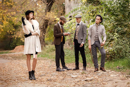 Gangsters in the forest. A girl smokes at her staring at one of the men. Retro concept.の写真素材