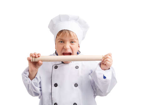 Little cook wants to bite a rolling pin on a white isolated backgroundの写真素材