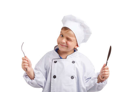 Little cook with fork and knife in hands on a white isolated backgroundの写真素材